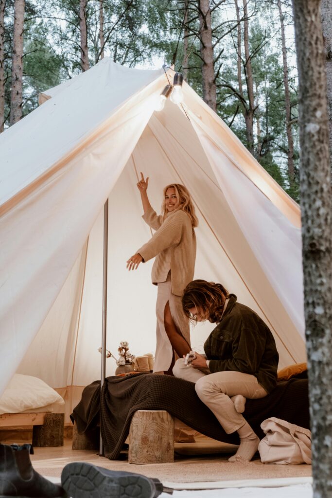 Young couple having fun inside a cozy tent in the woods, enjoying a camping adventure.